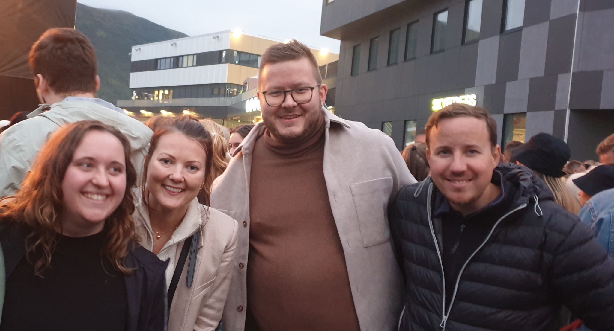To kvinner og to menn holder rundt hverandre og smiler til kamera