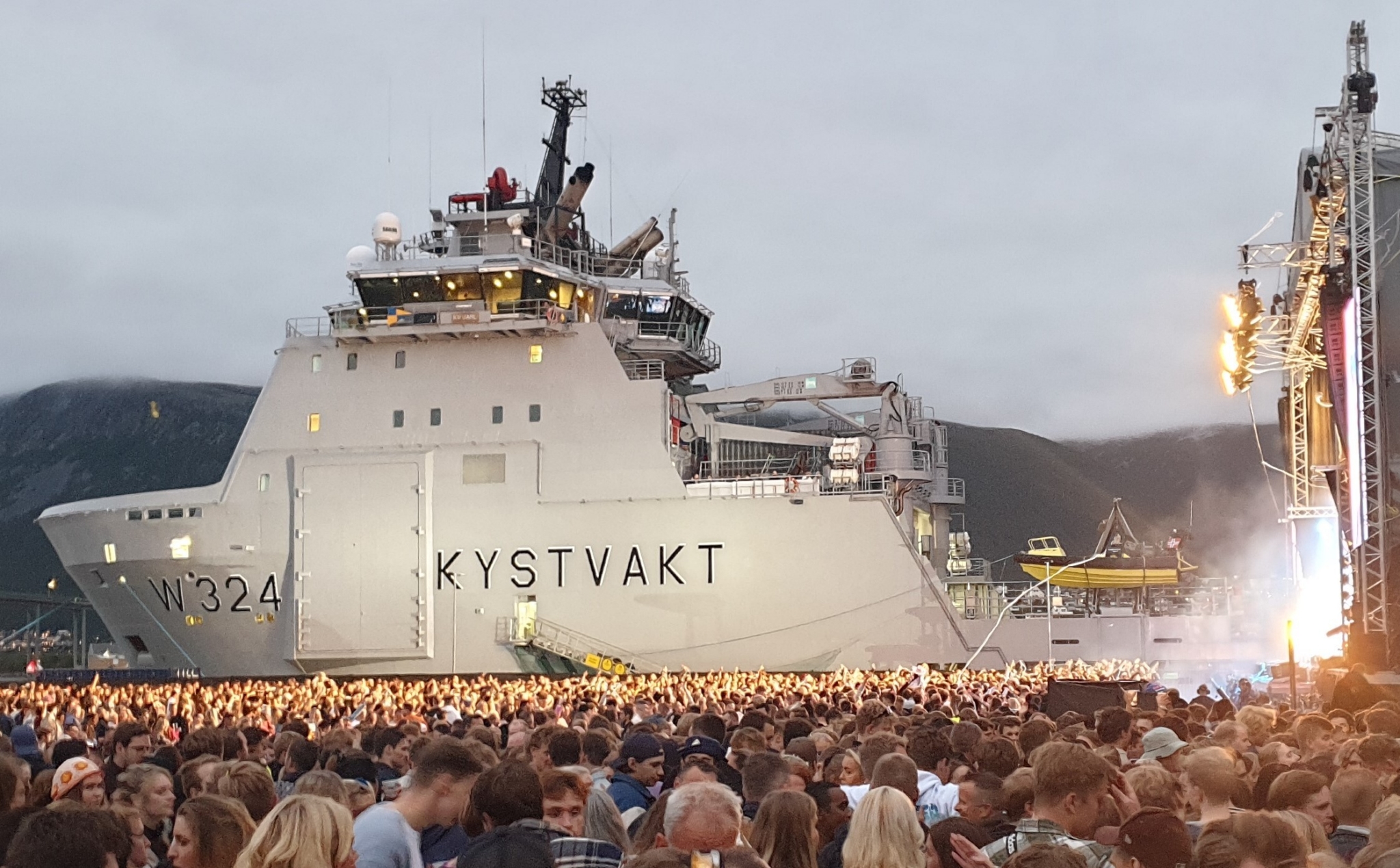 Bilde av festivalpublikum med kystvakt-skip i bakrgunn