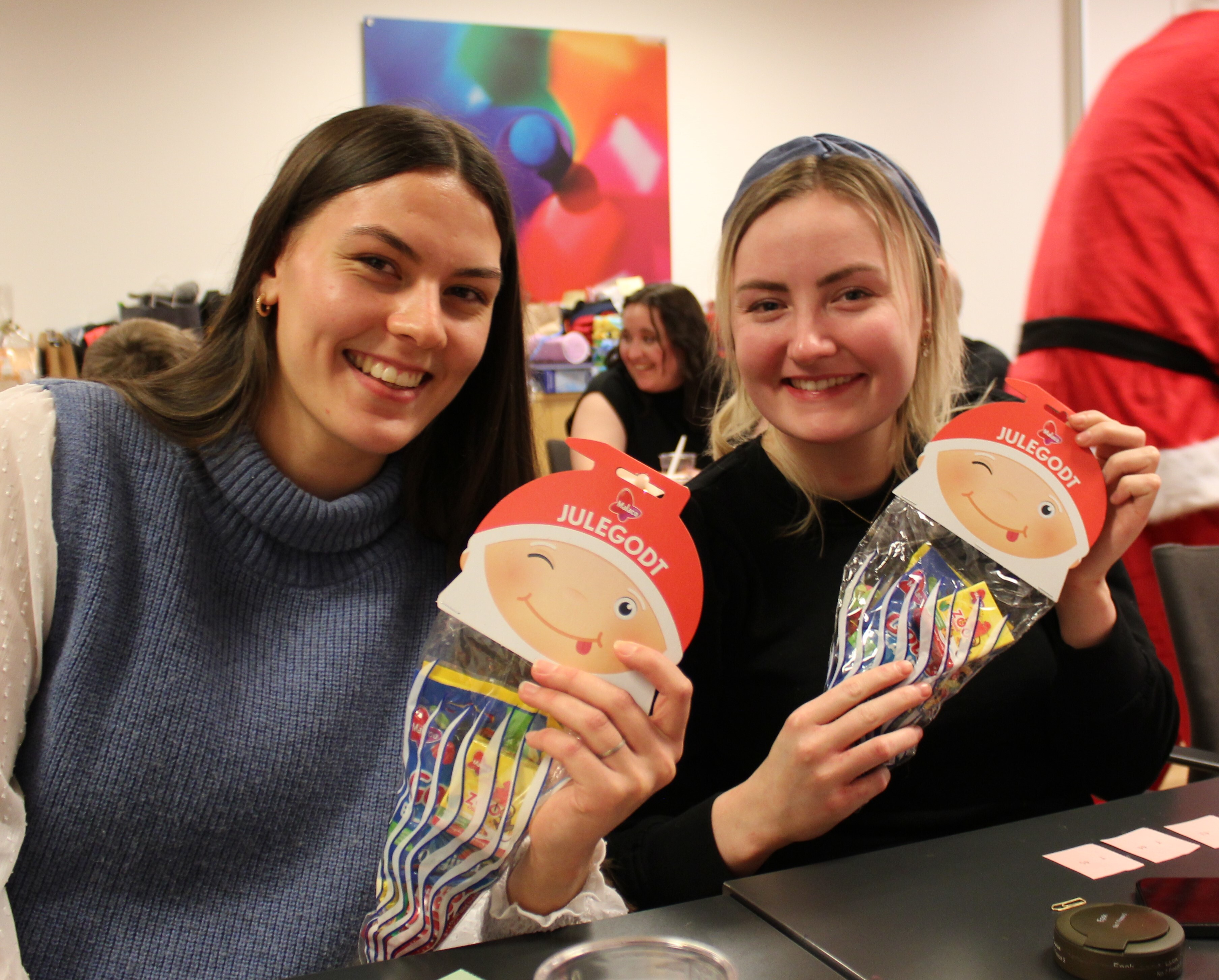 To jenter i tyveårene smiler og viser fram at de fikk godteri av julenissen