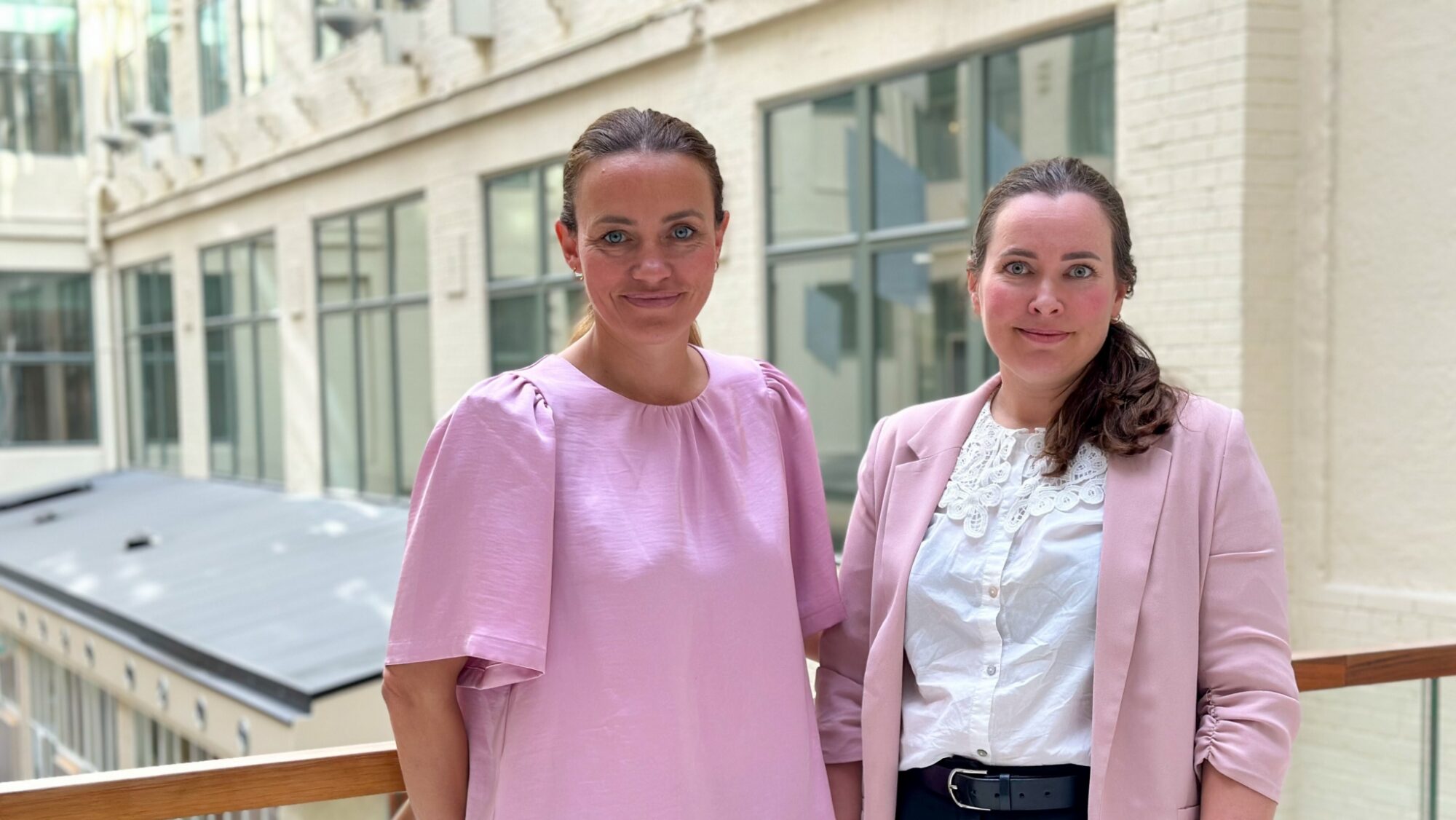 Ingrid og Annika står sammen foran en bygning og ser inn i kameraet.